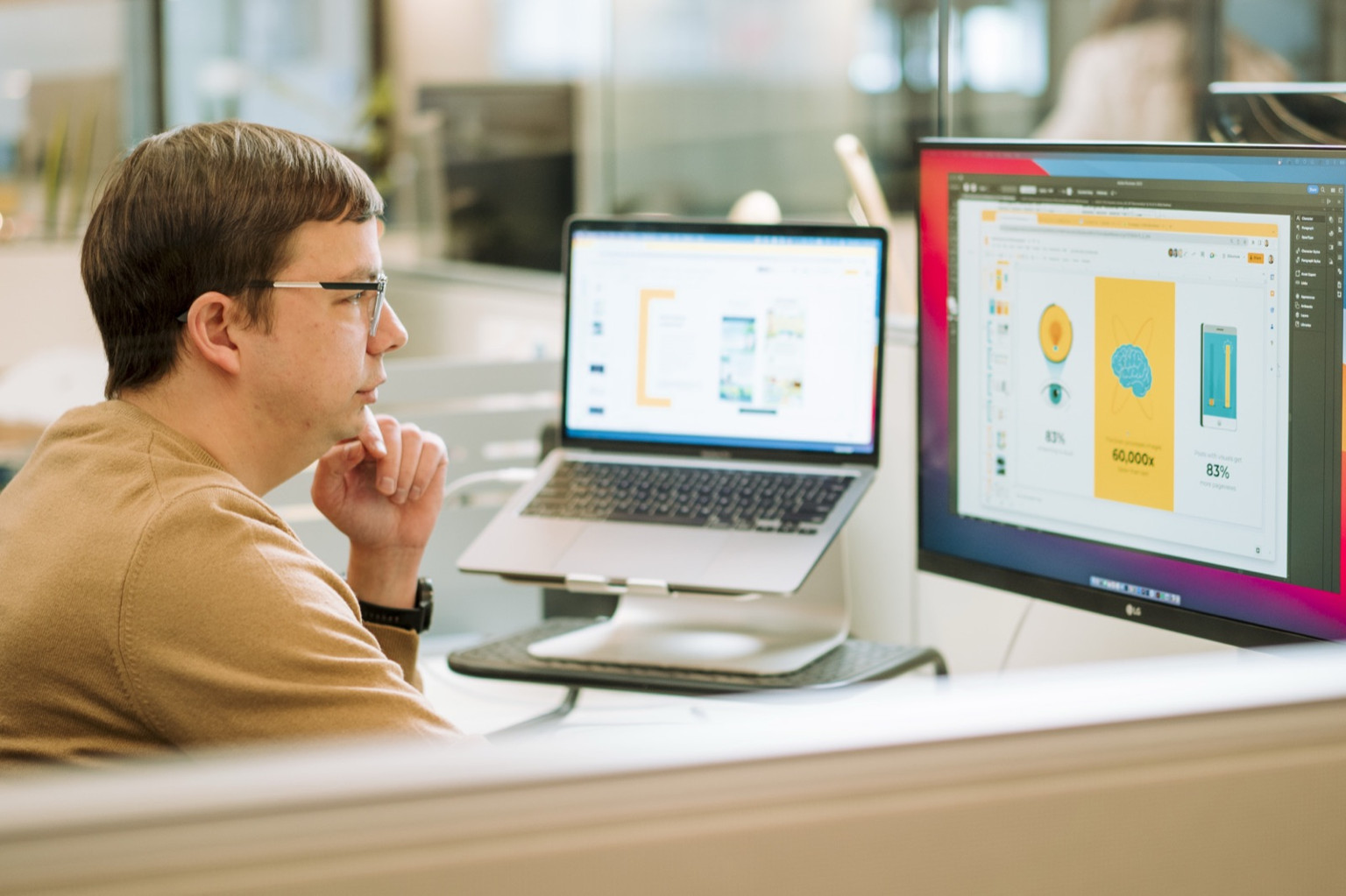 A Lemonly designer working on an infographic across two screens in the studio