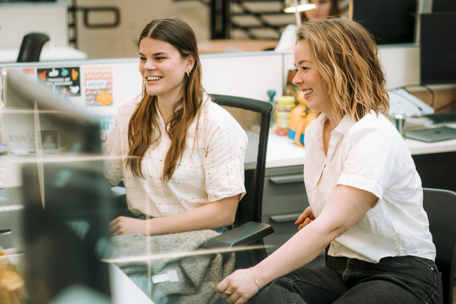 Two members of the Lemonly team reviewing work together at a desk in the studio